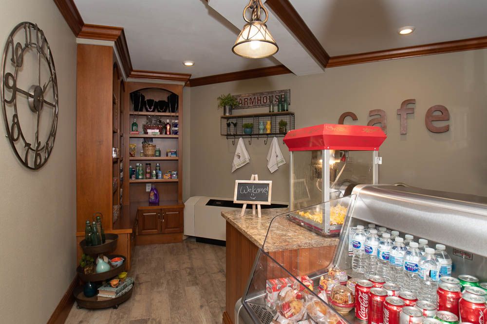 A cozy snack bar featuring a popcorn machine, beverage cooler, and various food items on shelves.