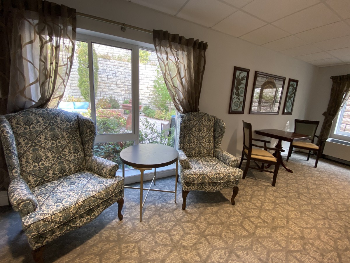 A cozy living room with patterned chairs and a small round table by the window.