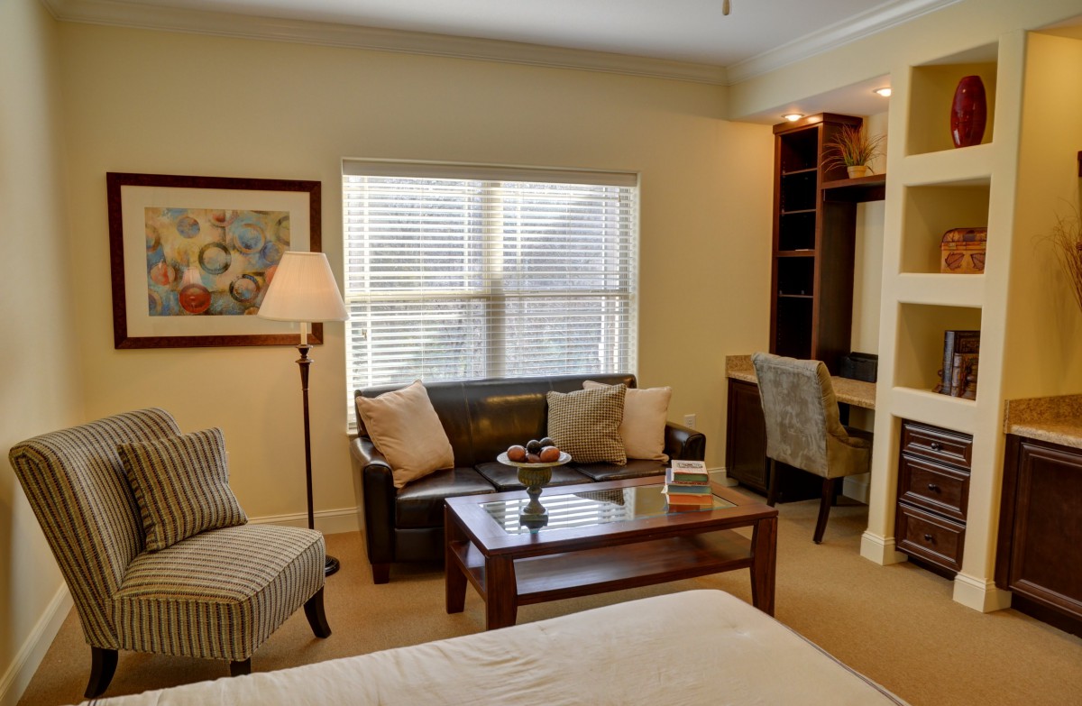 A cozy bedroom featuring a sofa, coffee table, desk, and seating area.