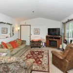 A cozy living room with a sofa, armchair, television, and fireplace.