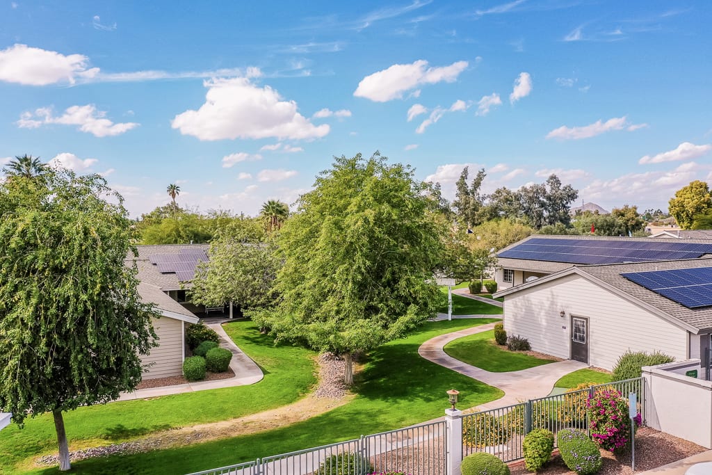 A serene suburban neighborhood with solar-paneled houses, lush greenery, and clear skies.