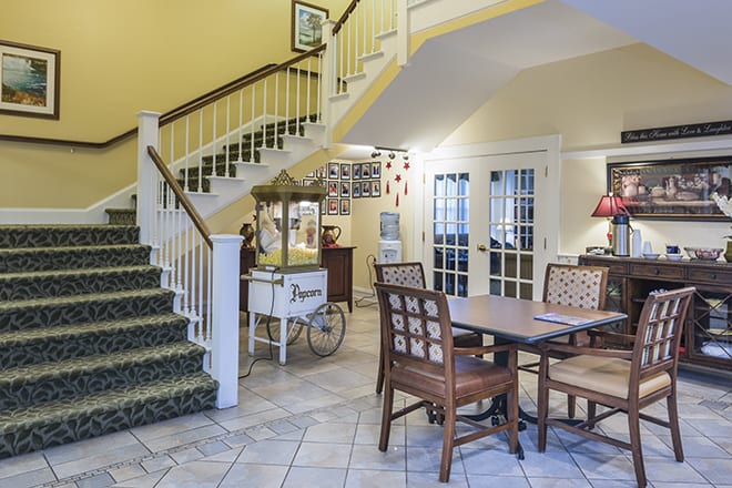A cozy interior featuring a staircase, a dining table, and a vintage popcorn machine.
