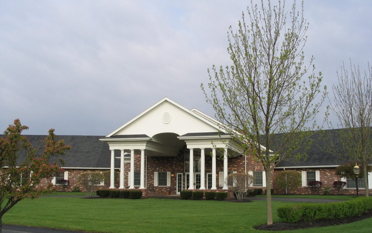 A brick building with tall white columns and a landscaped lawn.