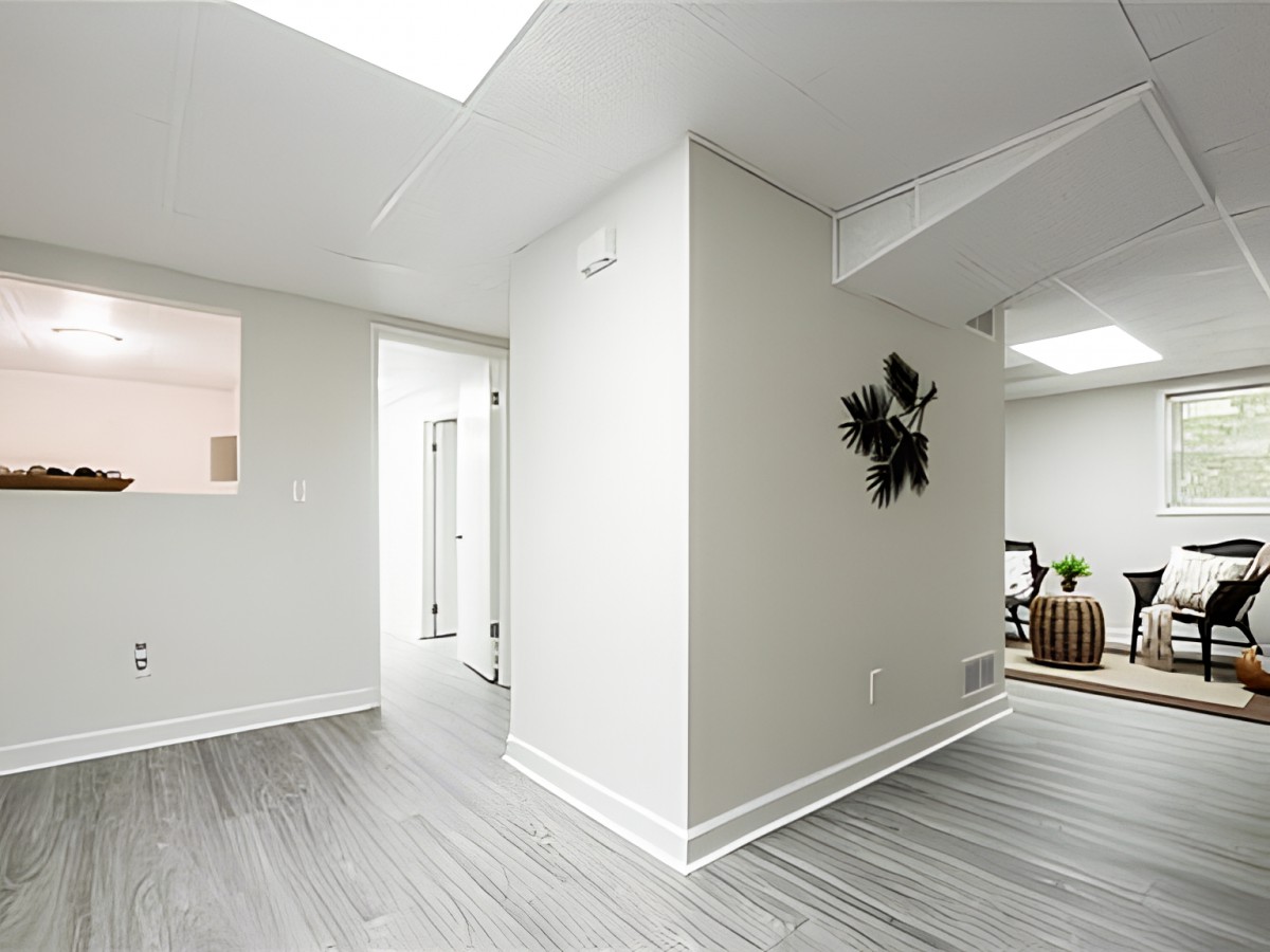 A modern, minimalist living space with white walls and wooden flooring.