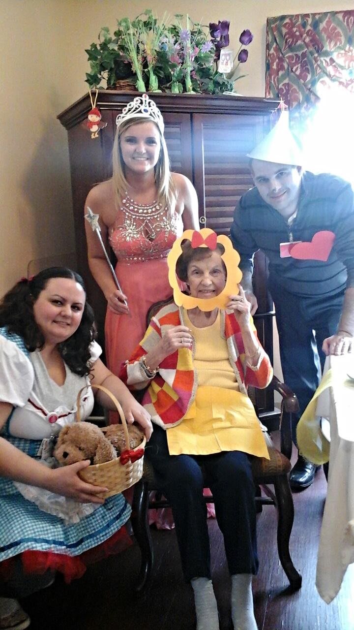 A group of people dressed in festive costumes, smiling and enjoying a celebration indoors.