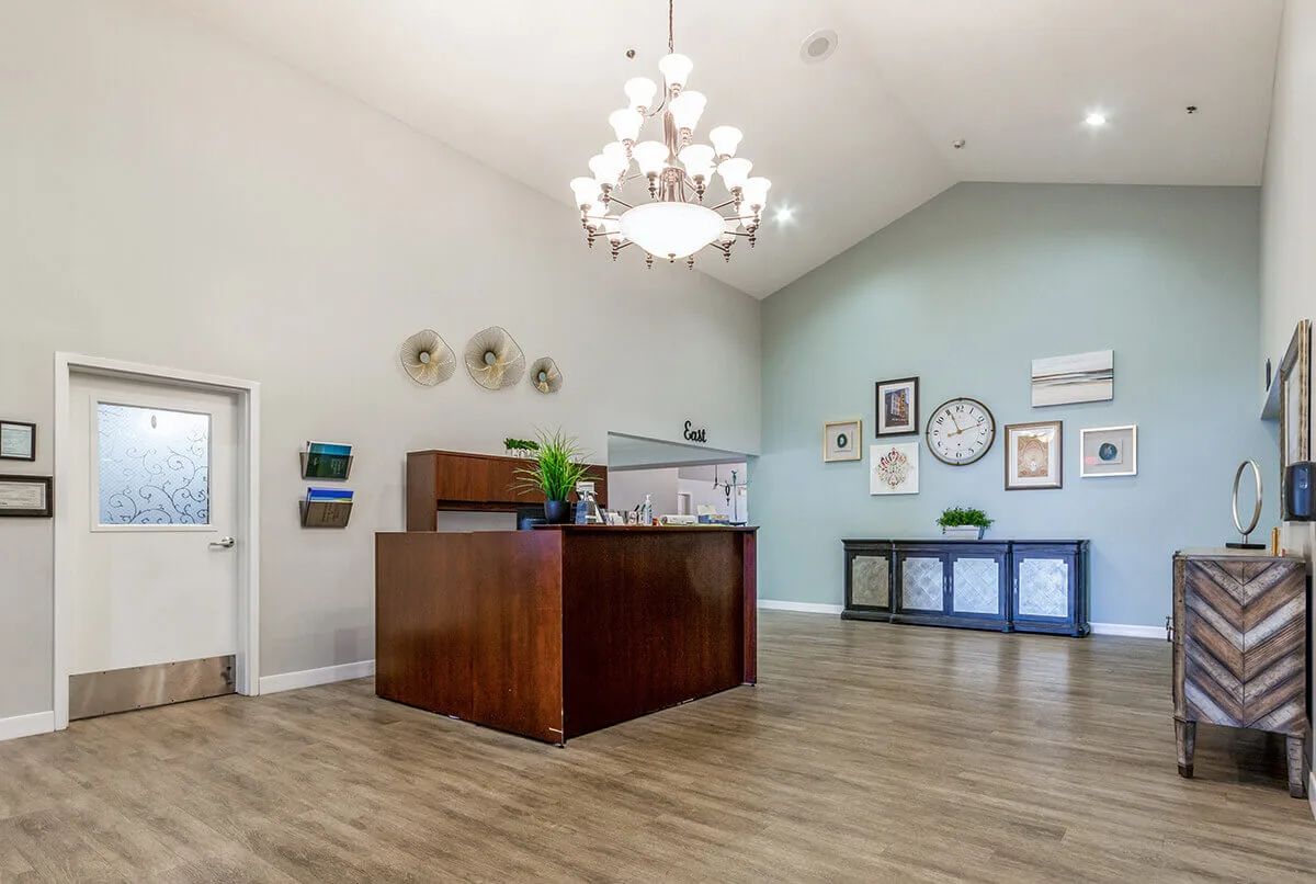 A modern reception area featuring wooden furniture and elegant wall decor under a decorative chandelier.