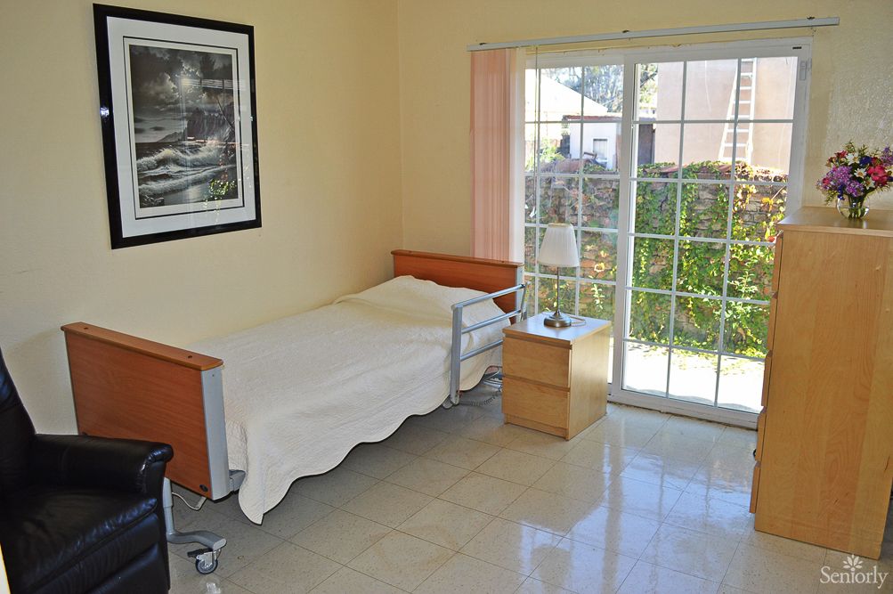 A minimalist bedroom with a single bed and a large window offering natural light.