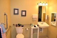 A neatly organized bathroom featuring a toilet, sink, and mirror with framed pictures on the wall.