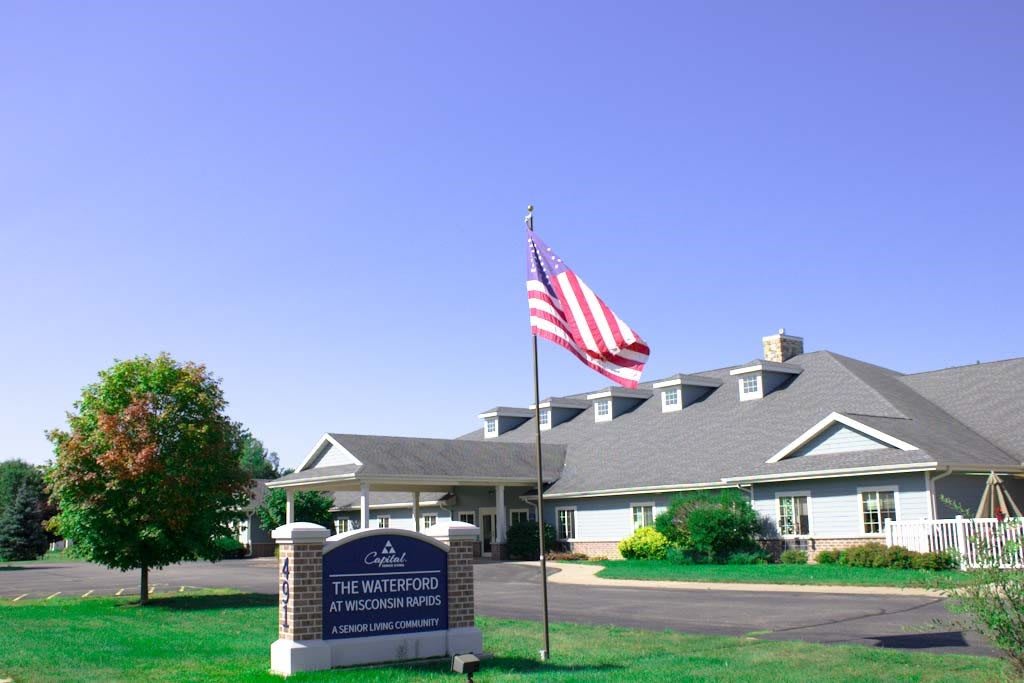 A building with an American flag and a sign in front, set against a clear blue sky.