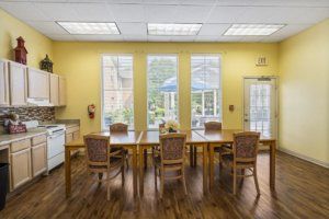 A bright and airy dining room with wooden tables, chairs, and large windows letting in natural light.