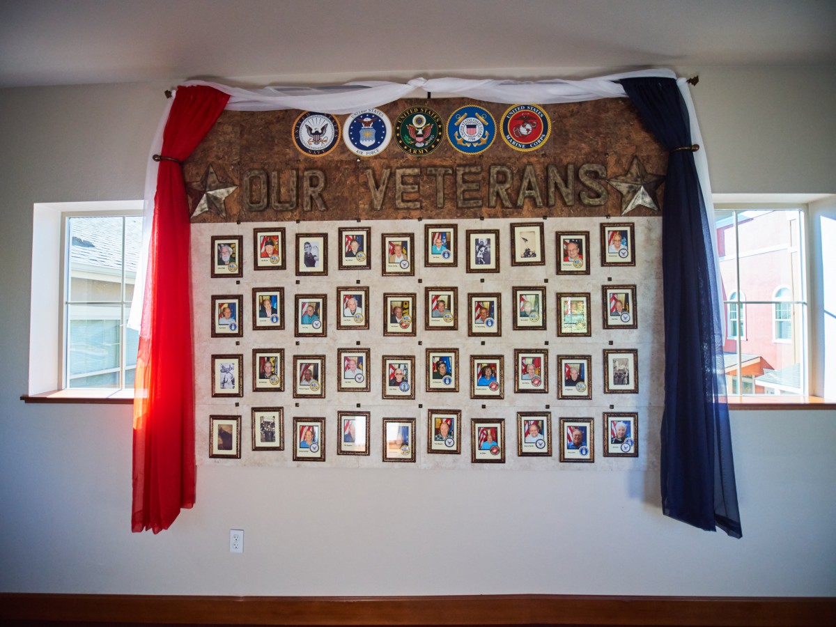 A wall display honoring veterans with photographs and military emblems.