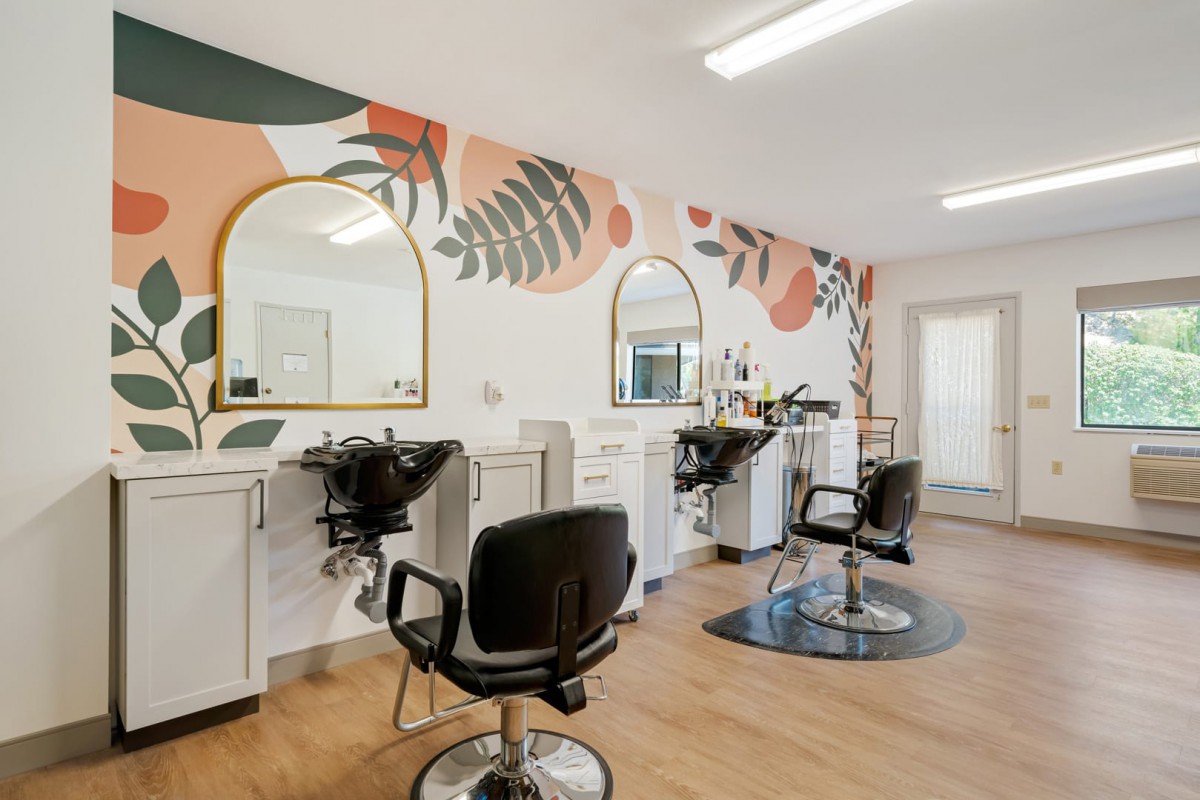 A modern hair salon interior featuring stylish chairs, mirrors, and colorful wall art.