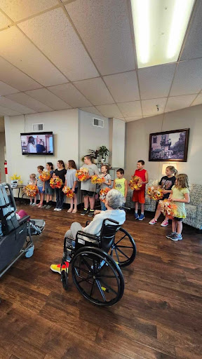 A group of children performing for residents in a care facility, bringing joy and community spirit.