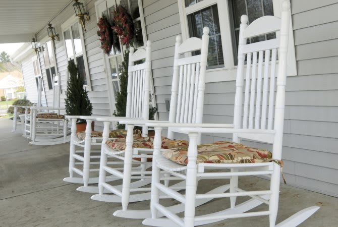 White rocking chairs on a cozy porch, adorned with wreaths and outdoor decorations.