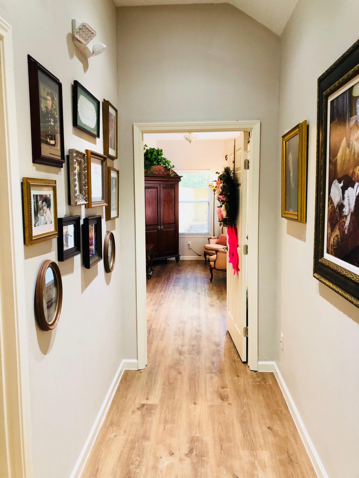 A cozy hallway with a gallery wall and wooden flooring leading into a sunlit room.