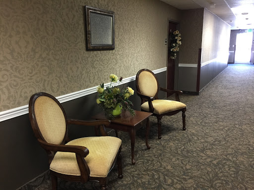 A cozy seating area in a hallway, featuring two elegant chairs and a small table adorned with flowers.