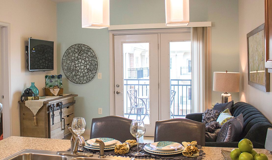 A modern dining room with an elegant table setting and French doors leading to a balcony.