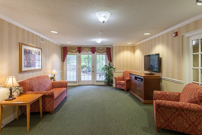 Cozy living room with sofas, a TV, and large windows draped with curtains.