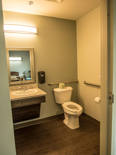 A clean and modern bathroom featuring a toilet, sink, and accessible handrails.