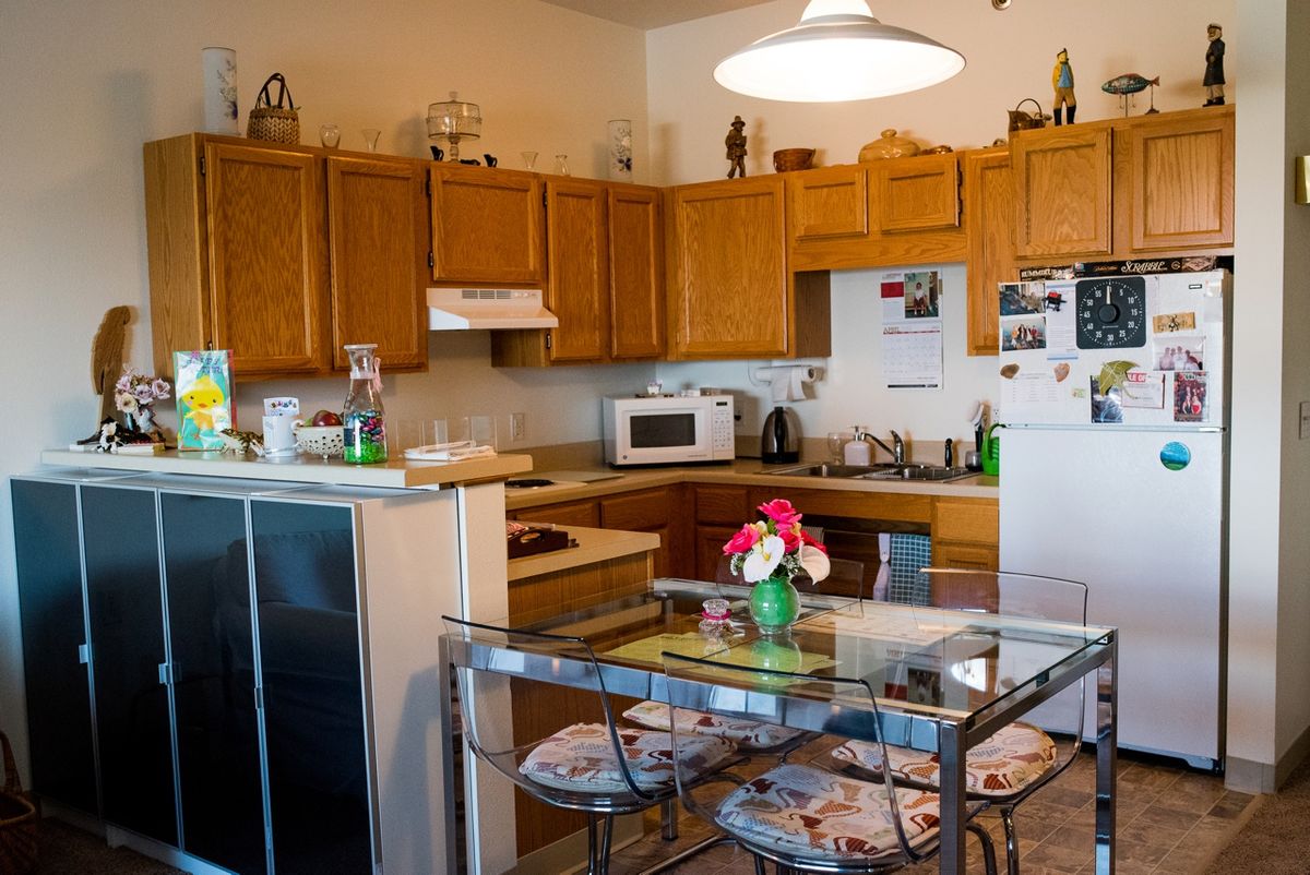 Cozy kitchen with wooden cabinets and a dining area featuring a glass table adorned with flowers.