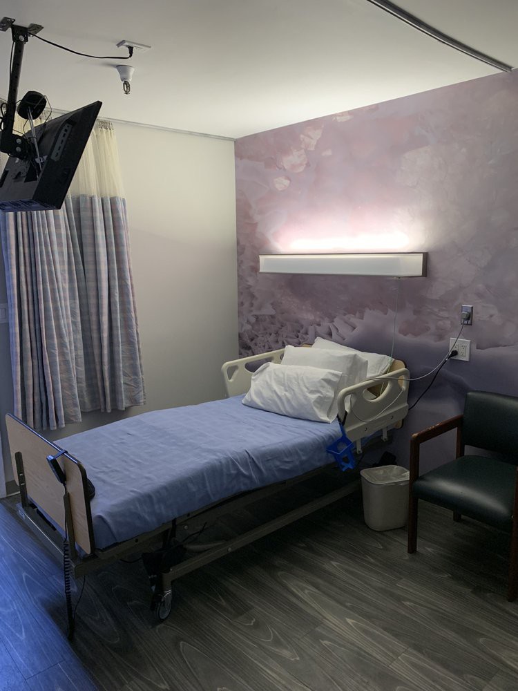 An empty hospital room with a bed and medical equipment.