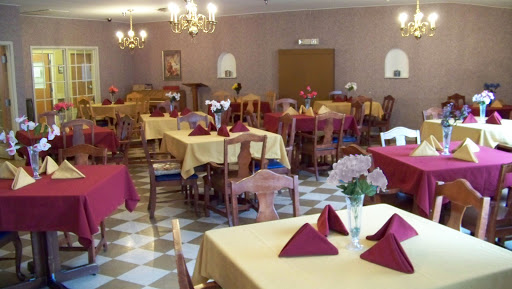 A cozy dining area set up for guests, featuring tables with yellow tablecloths and red napkins.