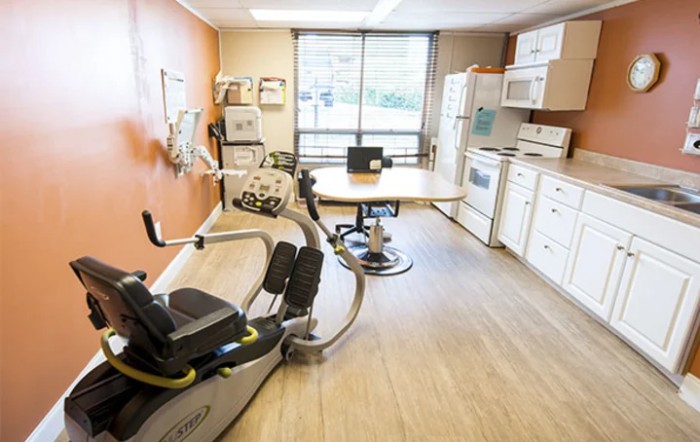 A multi-purpose room with kitchen amenities and exercise equipment, likely used for rehabilitation or therapy.