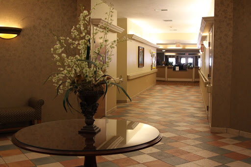 A view of a hotel lobby featuring a floral arrangement on a table, leading to the reception area.