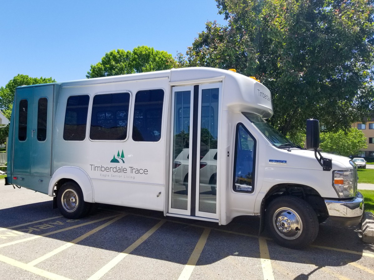 A white shuttle bus parked in a lot on a sunny day.