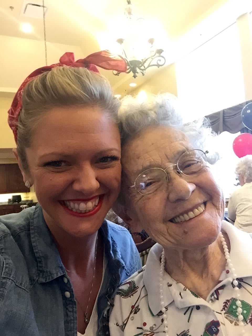 A joyful selfie of a young woman and an elderly woman indoors.