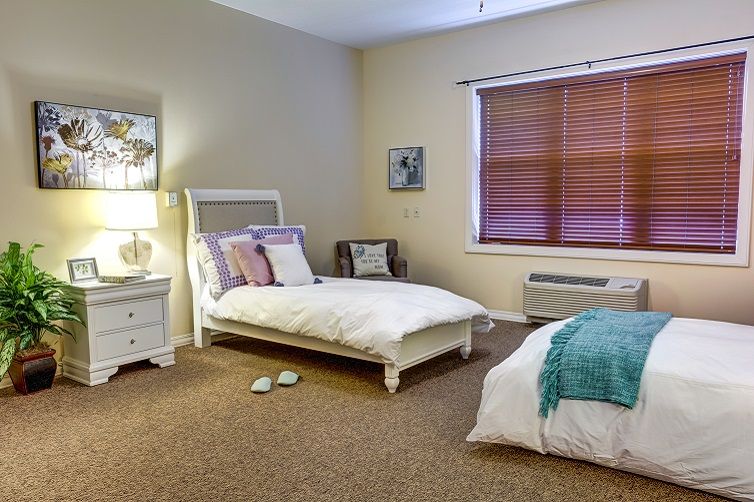 A cozy bedroom with twin beds, soft lighting, and warm decor.