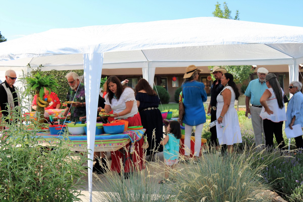 A group of people enjoying an outdoor gathering under a tent on a sunny day.
