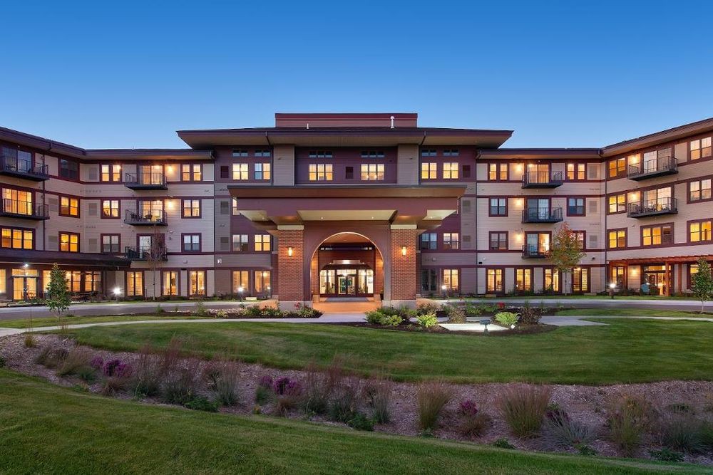 A modern residential building with well-maintained landscaping in the evening.