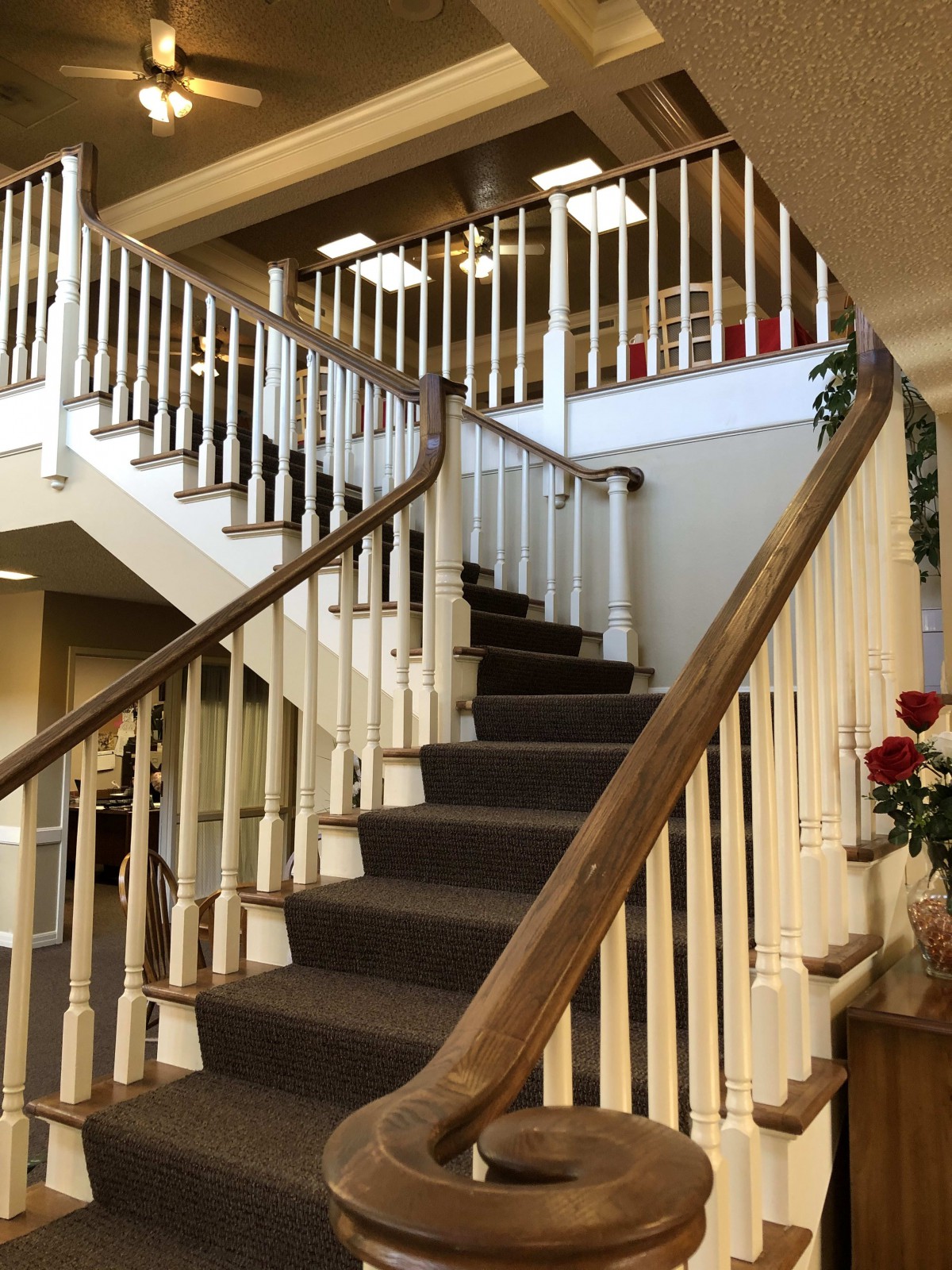 A carpeted staircase with a wooden handrail inside a building.