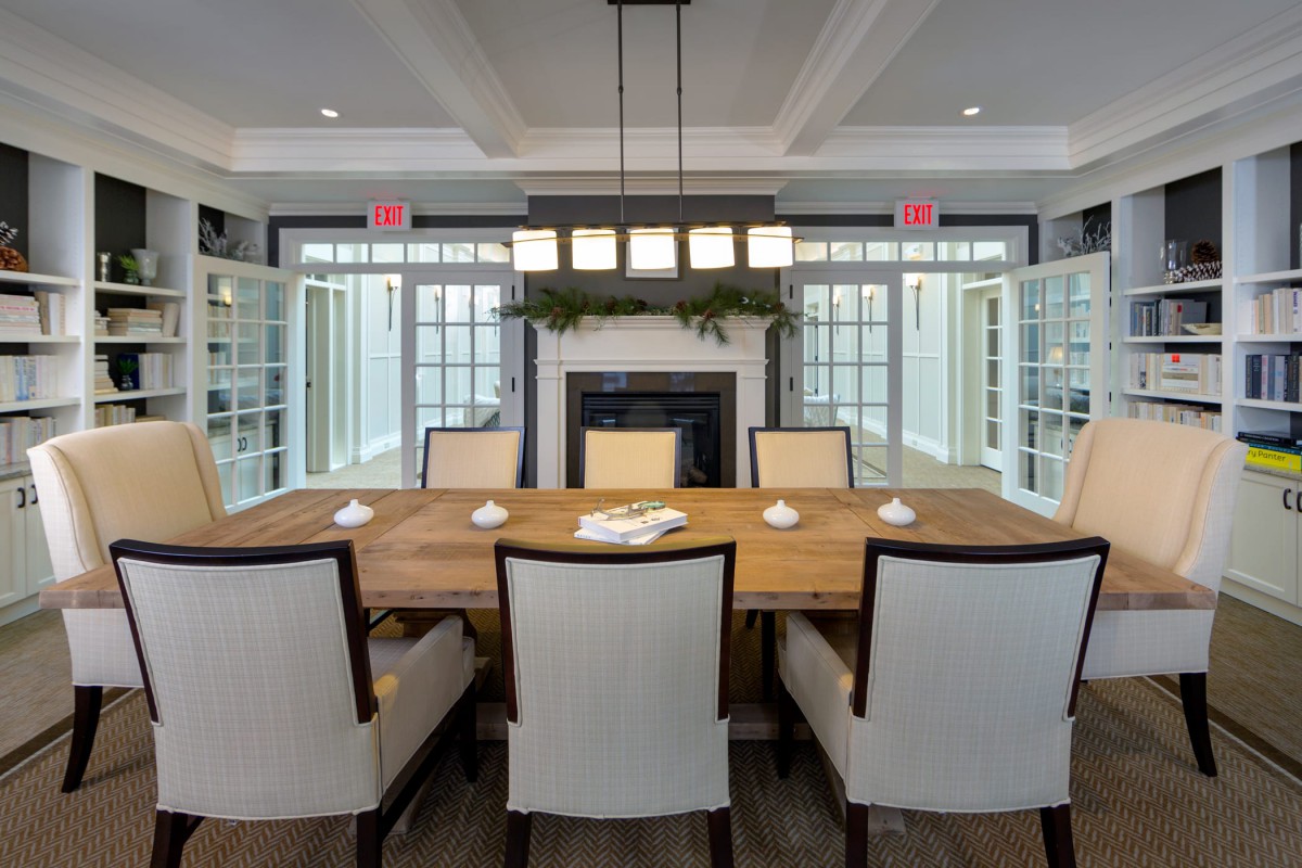 A modern dining room with a wooden table, upholstered chairs, and a fireplace.