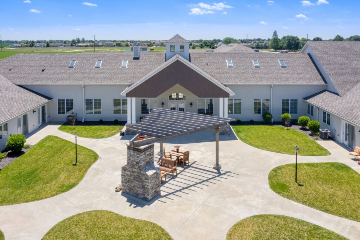A large building with a central patio area and surrounding lawn under a clear blue sky.