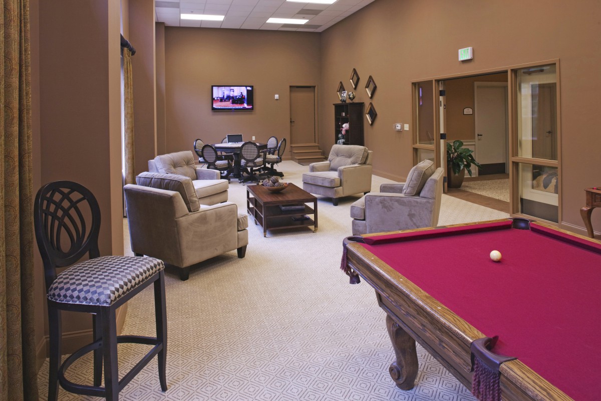 A comfortable lounge area with a pool table, plush chairs, and a television.
