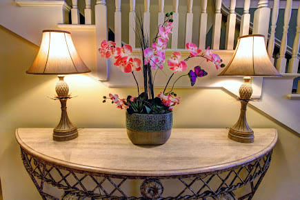 A beautifully arranged orchid centerpiece with two lamps on a decorative table.