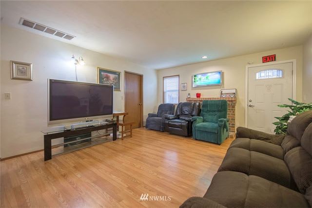 A cozy living room with a large television, comfortable seating, and hardwood floors.
