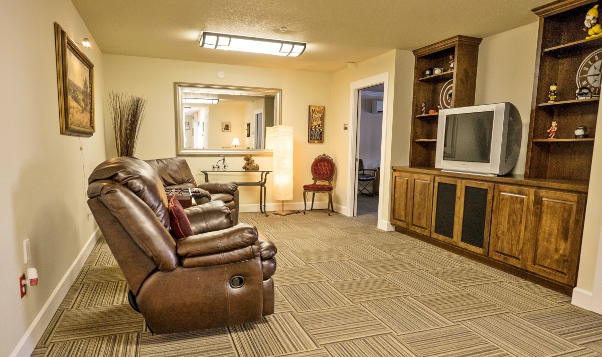 A cozy living room featuring leather recliner chairs, a large television, and built-in shelving.