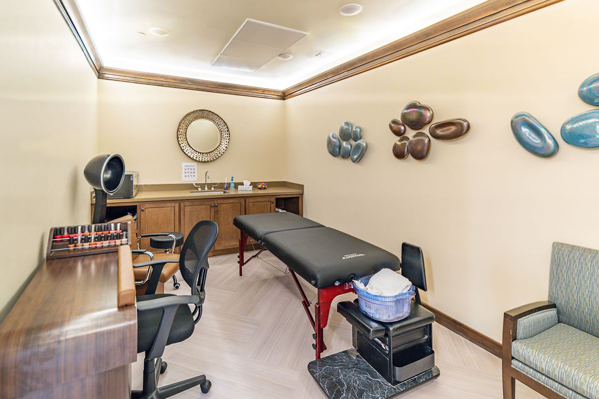 A cozy therapy room with a massage table, office chair, and decorative wall art.