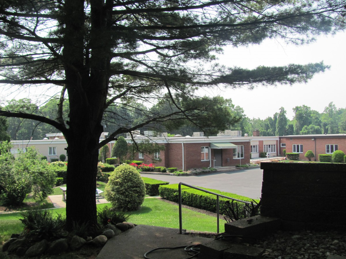 A scenic view of a landscaped area with buildings, surrounded by trees and greenery.