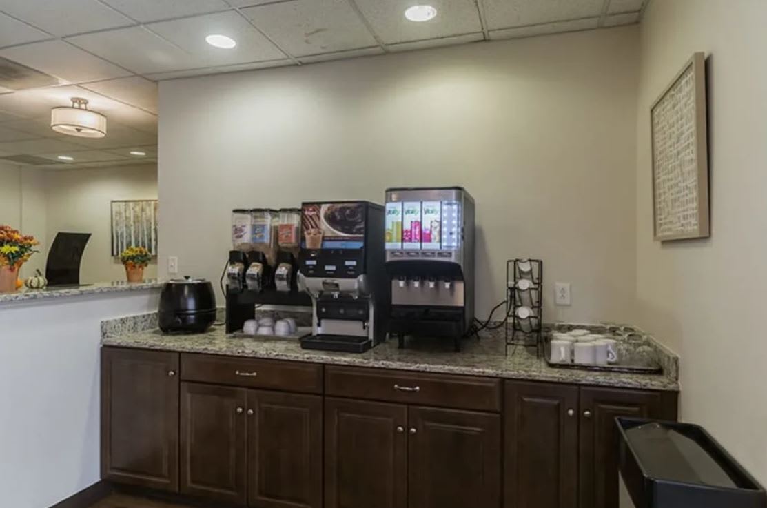 A beverage station featuring coffee machines and drink dispensers on a countertop in a kitchen area.