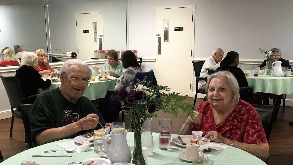 Elderly individuals enjoying a meal together in a communal dining area.