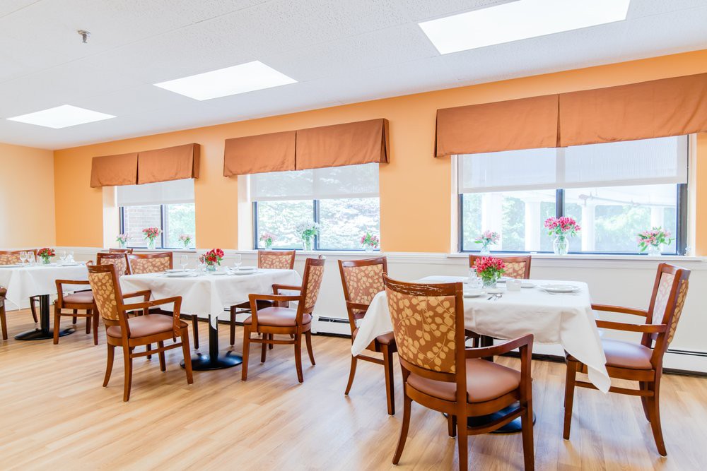 A bright and well-decorated dining room with neatly arranged tables and chairs near large windows.