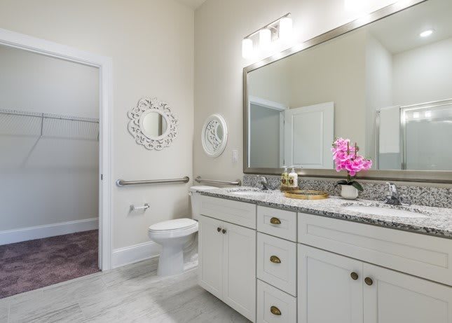 A modern bathroom with bright lighting, featuring a large mirror, sink, and decorative elements.