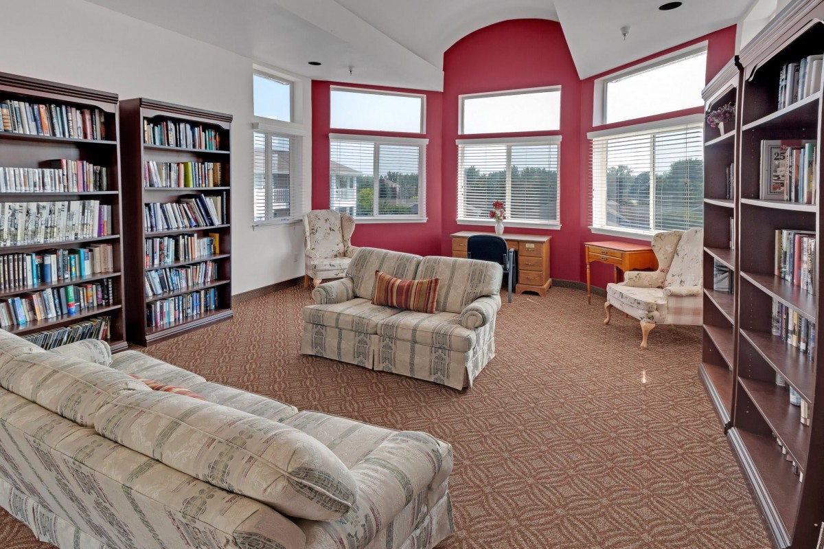 A cozy living room with sofas, a bookshelf, and large windows.