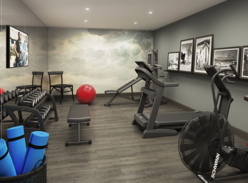 A modern gym room featuring a treadmill, dumbbells, and other exercise equipment.