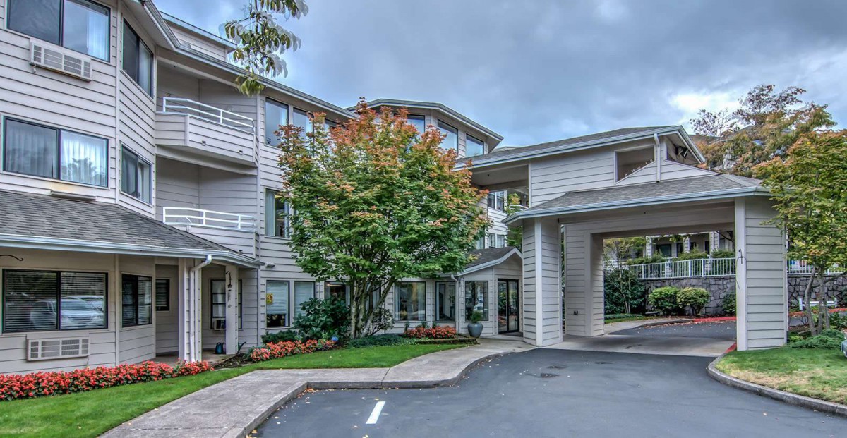 A modern residential building with a landscaped entrance and greenery.