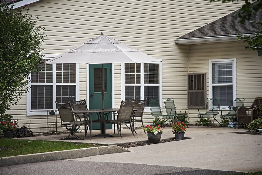 A patio area with a table, chairs, and potted plants in front of a house.